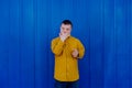 Happy young man with Down syndrome smiling and looking at camera against blue background. Royalty Free Stock Photo