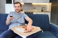 Happy young man drinking beer and eating pizza when watching game on tv at home Royalty Free Stock Photo