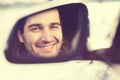 Happy young man driver looking in car side view mirror Royalty Free Stock Photo