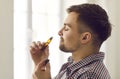 Happy young man enjoying aromatherapy and smelling essential oil from roller bottle