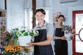 happy young man florist wearing apron holding bucket flower smiling looking at camera. working in flower shop Royalty Free Stock Photo