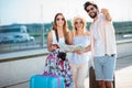 Happy young man giving directions to two female tourists, standing in front of an airport terminal building