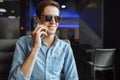 Happy young man in glasses, emotionally talking on the phone, sitting in a cafe, suitable for advertising, text insertion Royalty Free Stock Photo