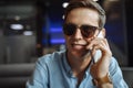 Happy young man in glasses, emotionally talking on the phone, sitting in a cafe, suitable for advertising, text insertion Royalty Free Stock Photo