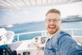 Happy young man goes on trip on white yacht sea making selfie photo on camera, concept travel life hipster Royalty Free Stock Photo