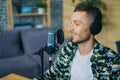 Happy young man in headphones talking in microphone in recording studio