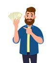 Happy young man holding cash/money/banknotes and pointing his index finger towards that. Financial money concept. Human emotion.