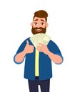 Happy young man holding cash/money/banknotes and showing thumbs up or like sign. Financial money concept. Human emotion concept. Royalty Free Stock Photo