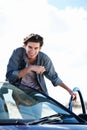 Ready to hit the road. Happy young man holding a cellphone and leaning on the roof of his car while smiling at the Royalty Free Stock Photo