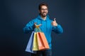 Happy young man holding colorful shopping bags and showing thumb up, Royalty Free Stock Photo
