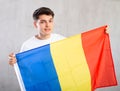 Happy young man holding flag of Romania against unicoloured background Royalty Free Stock Photo