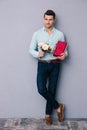 Happy young man holding gift box and flowers Royalty Free Stock Photo