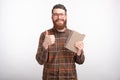 Happy young man is holding a notebook or a book, smiling at the camera, showing like button or thumb up on white Royalty Free Stock Photo