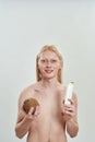 Happy young man holding shampoo bottle and coconut Royalty Free Stock Photo