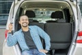 Happy young man holds a car key in the car trunk Royalty Free Stock Photo