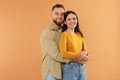 Happy young man hugging his girlfriend posing on orange background Royalty Free Stock Photo