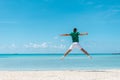 Happy young man jumping with outstretched arms on the beach. Summer vacation concept Royalty Free Stock Photo