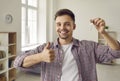 Happy young man with key to new home showing thumbs up while evaluating real estate purchase. Royalty Free Stock Photo