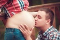 Happy young man kisses his pregnant wife belly