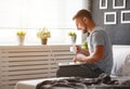 Happy young man with laptop and cup of coffee in bed Royalty Free Stock Photo