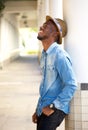 Happy young man leaning against wall laughing Royalty Free Stock Photo