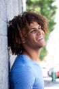Happy young man leaning against wall and laughing Royalty Free Stock Photo