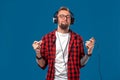 Happy young man listening to music with headphones. Handsome smiling guy in checkered shirt with closed eyes dancing Royalty Free Stock Photo