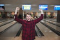 Happy young man made a bowling strike. The student raised his hands from joy while playing bowling. Bowling victory.