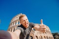 Happy young man making selfie thumb up sign in front of Colosseum in Rome, Italy. Concept travel trip Royalty Free Stock Photo