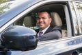 Happy young man of Middle Eastern appearance in business suit is driving an expensive car. The man is happy to buy a car