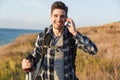 Happy young man outside in free alternative vacation camping talking by mobile phone Royalty Free Stock Photo