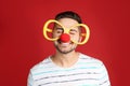 Happy young man with party glasses and clown nose on background. April fool`s day Royalty Free Stock Photo