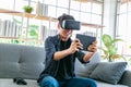 Happy young man is playing racing videogame in 3D virtual reality simulator using headset in living room Royalty Free Stock Photo