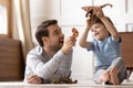 Happy young man playing toys with joyful small schoolboy. Royalty Free Stock Photo