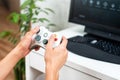 Happy young man playing and winning online game on computer. Back view of gamer with video console gamepad controller. Competitive Royalty Free Stock Photo