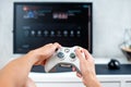 Happy young man playing and winning online game on computer. Back view of gamer with video console gamepad controller. Competitive Royalty Free Stock Photo