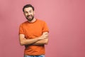 Happy young man. Portrait of handsome young man in casual keeping arms crossed and smiling while standing against pink background Royalty Free Stock Photo