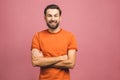 Happy young man. Portrait of handsome young man in casual keeping arms crossed and smiling while standing against pink background Royalty Free Stock Photo