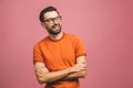 Happy young man. Portrait of handsome young man in casual keeping arms crossed and smiling while standing against pink background Royalty Free Stock Photo