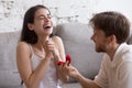 Happy young man propose to his girlfriend sitting on sofa Royalty Free Stock Photo