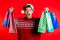 Happy young man in Santa hat.colorful paper bags after shopping isolated on red Royalty Free Stock Photo