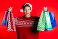 Happy young man in Santa hat.colorful paper bags after shopping isolated on red Royalty Free Stock Photo