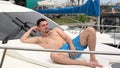 A young man in shorts lies and tans on a boat.