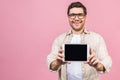 Happy young man showing blank tablet computer screen and looking at the camera isolated over pink background Royalty Free Stock Photo