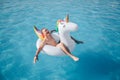 Happy young man sits in white float and enjoy. He smiles and keeps eyes closed. Guy is in pool alone.