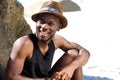 Happy young man sitting at the beach with hat Royalty Free Stock Photo