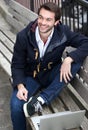 Happy young man sitting on bench with laptop Royalty Free Stock Photo