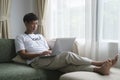 Happy young man sitting on couch in living room and using laptop computer Royalty Free Stock Photo