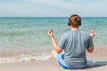 Happy young man sitting on the beach listening to music on headphones. Yoga and relax Royalty Free Stock Photo