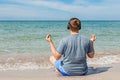 Happy young man sitting on the beach listening to music on headphones. Yoga and relax Royalty Free Stock Photo